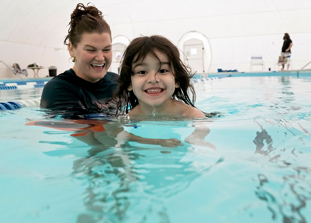 swim instructor helping a little child in the pool