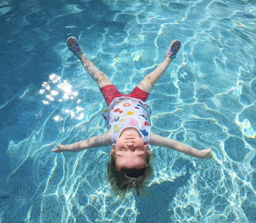 child floating in swimming pool