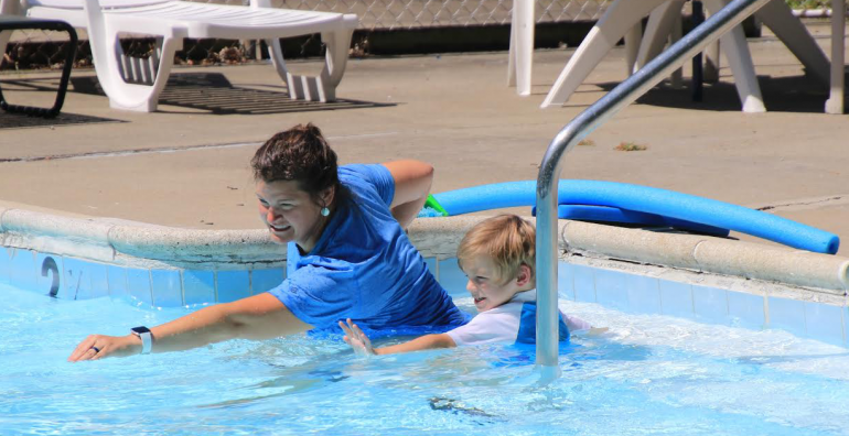 Showing stroke technique in water to young swimmer